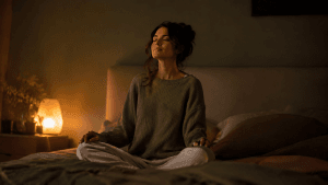 Persona en su dormitorio con luz cálida y tenue practicando una técnica de relajación para bajar la ansiedad por la noche